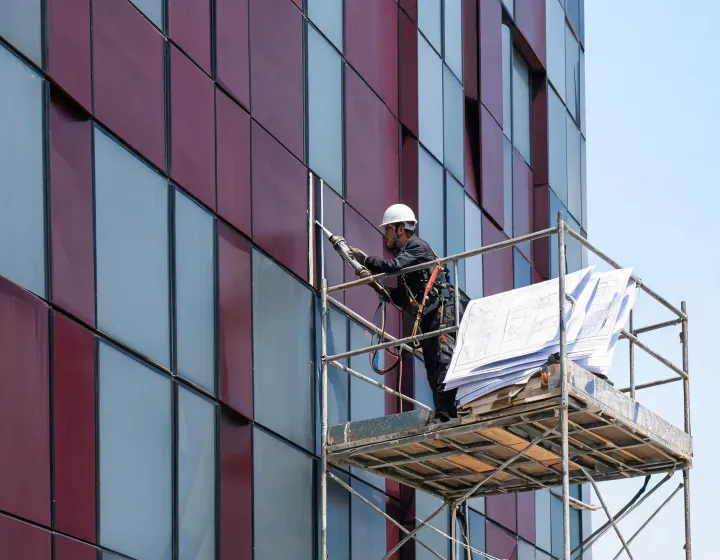 Technician tooling a curtainwall sealant joint on a commercial facade